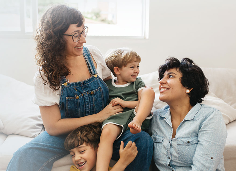 Two women playing with their kids in their living room.