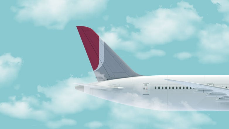 airplane with a burgundy j-mark flying in a cloudy sky.