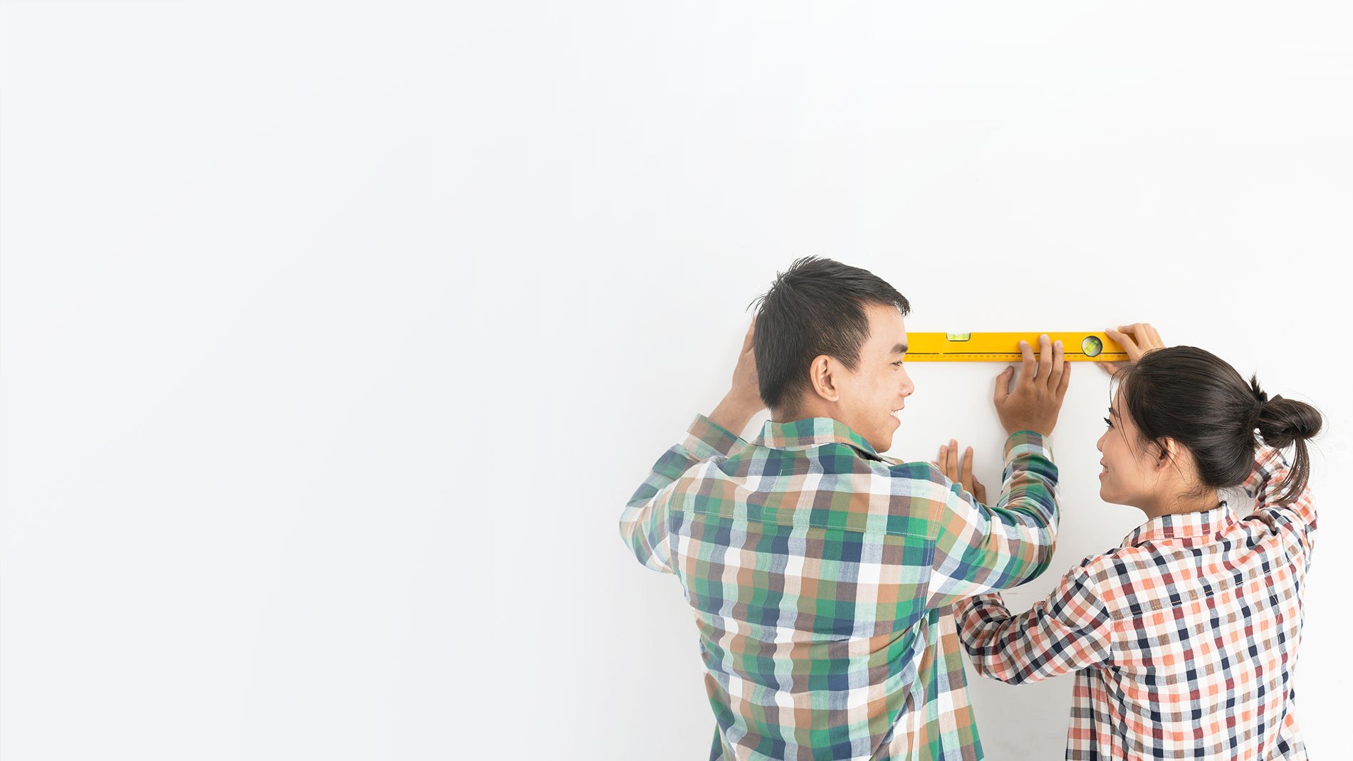 man and woman using a level on a wall.
