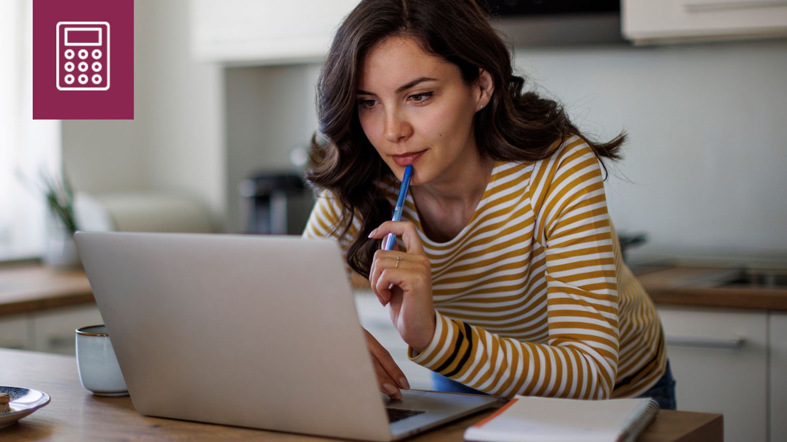 Woman in striped shirt using laptop computer to compare savings rates while sitting at kitchen table with coffee.