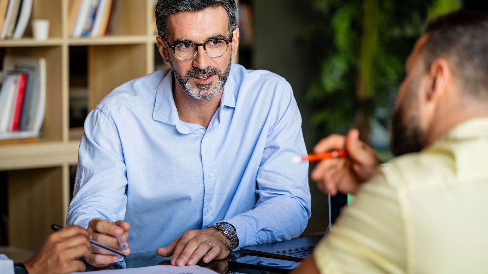 Two people seated at a table during a financial planning discussion, reviewing retirement savings strategies and ways to increase 401(k) contributions.