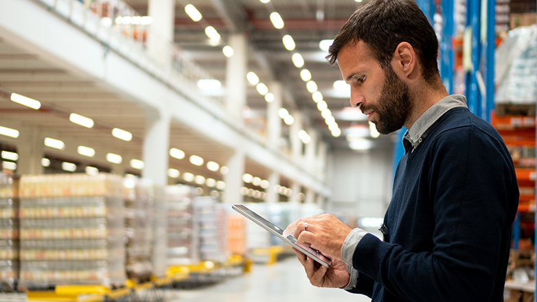 manufacturing business owner looking at tablet in warehouse