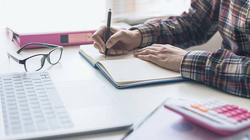 man at desk taking notes