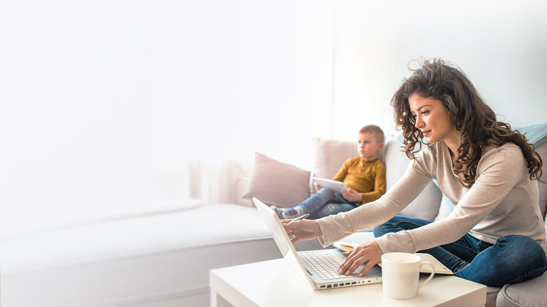 woman sitting on the couch with her son using a laptop computer.