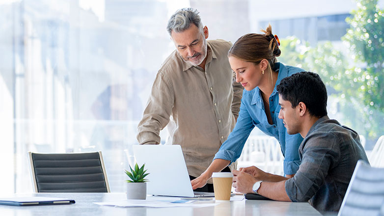colleagues looking at laptop in conference room