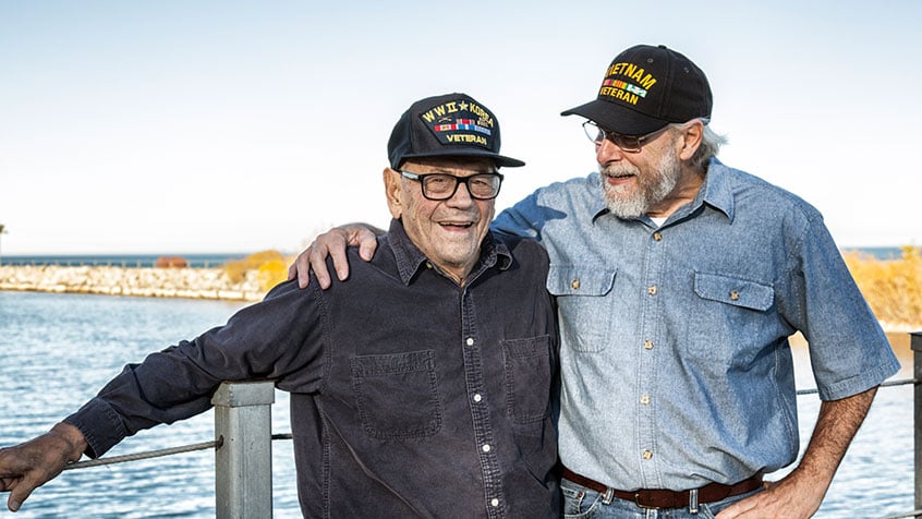 Veteran father and son standing together on a pier.