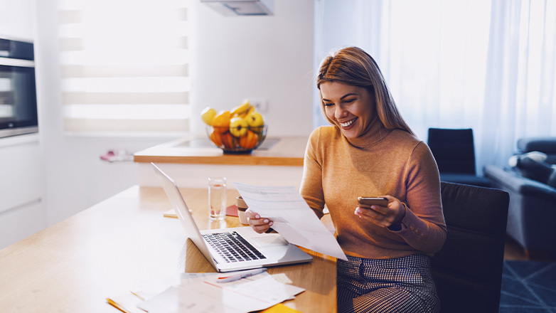 woman at a table looking at paper and laptop