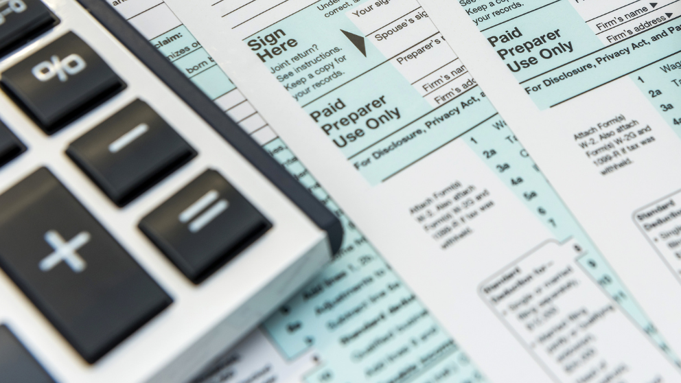 a corner of a calculator over tax documents