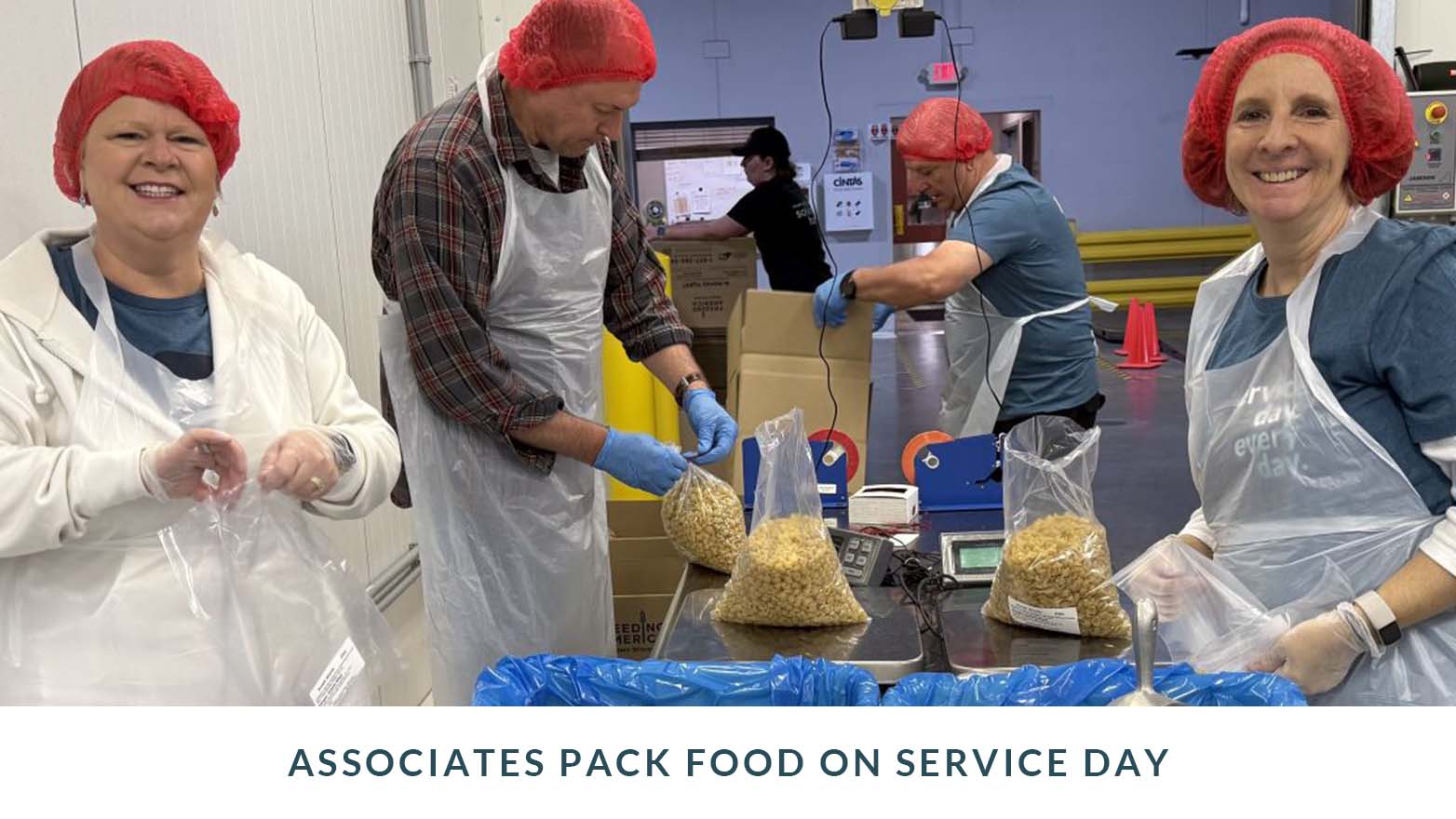 Group of people indoors wearing food‑safe hair coverings, gloves, and aprons while packing food into clear bags at a work table. Caption below reads “Associates pack food on Service Day.”