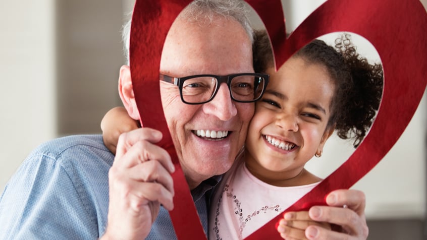 elderly man and little girl holding up heart frame