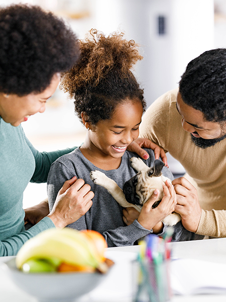 african american family and daughter holding a puppy smiling