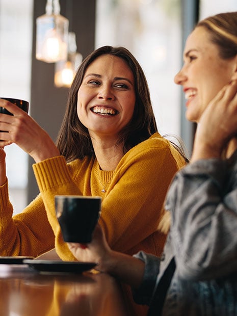 young female friends smiling together in a coffee shop