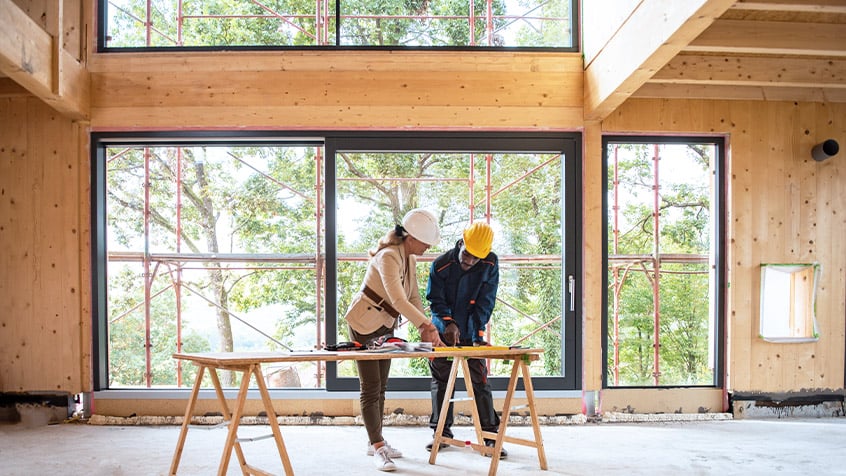 architecht reviewing plans with builder in a partially constructed house.