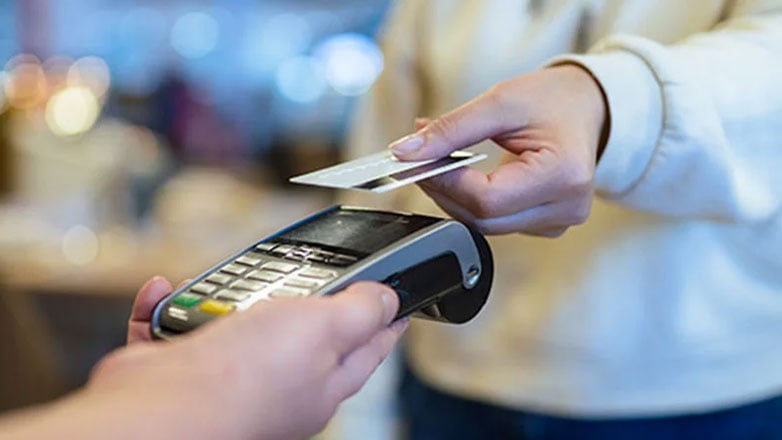 Customer uses their debit card at a contactless card reader in a store.