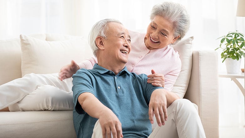 Older couple laying on couch talkng with each other.