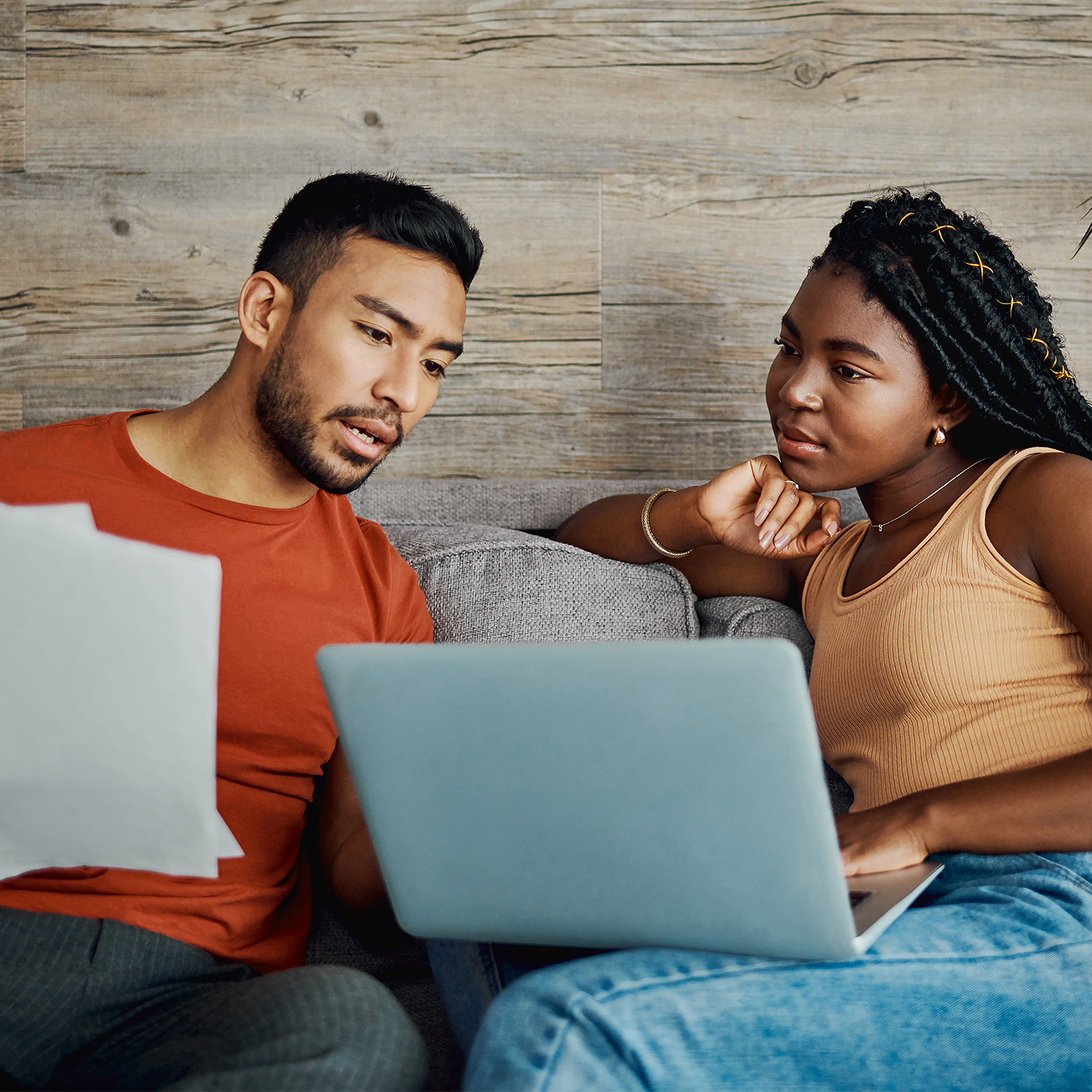 african american couple sitting on the couch looking at a laptop