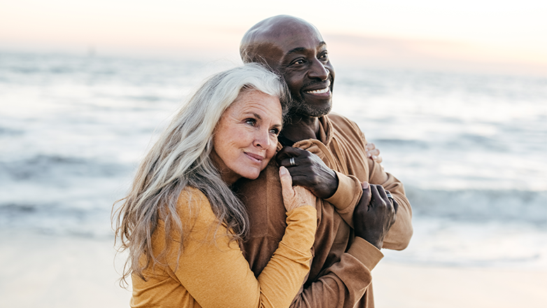 biracial couple walking on the beach