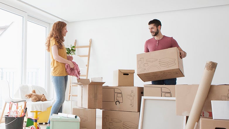 Couple standing in their new home surrounded by boxes from their move.