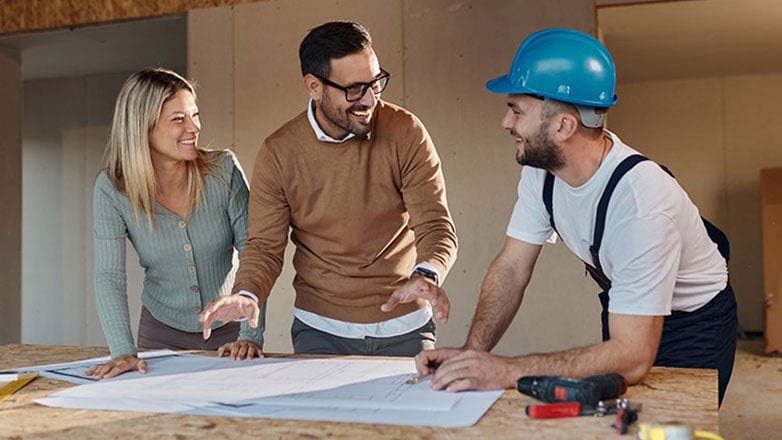 Contractor reviews building plans with homeowners.