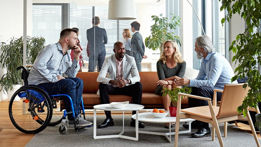 diverse group of employees sitting around a coffee table having a conversation.