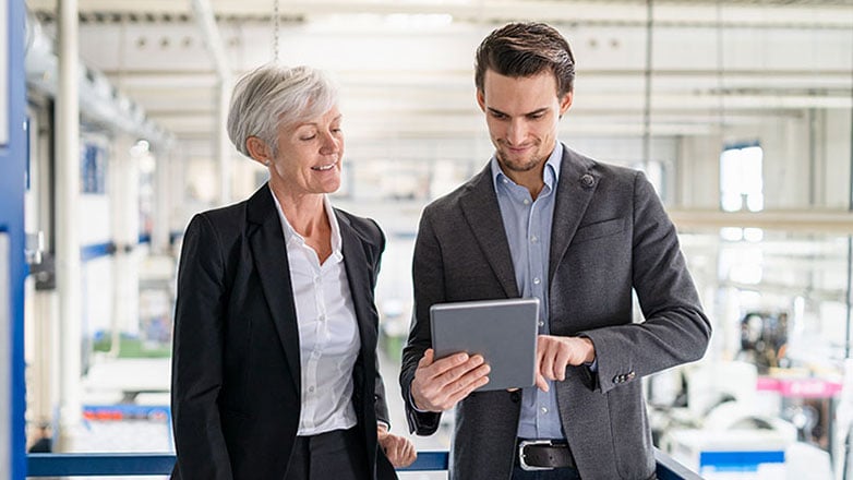 Son discusses business succession plan with his mother in a factory.