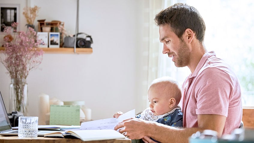 father holding baby while looking at papers