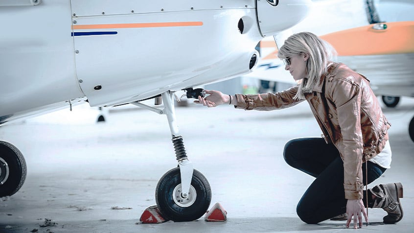 female pilot inspecting the plane wheel.