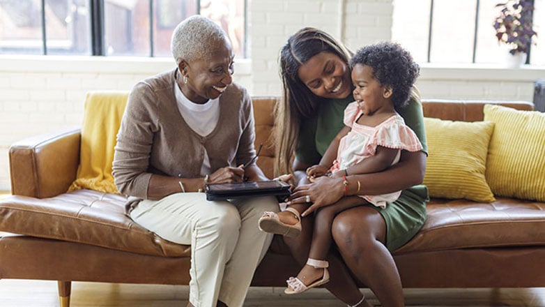 Grandma, mom and baby relax on the couch together.