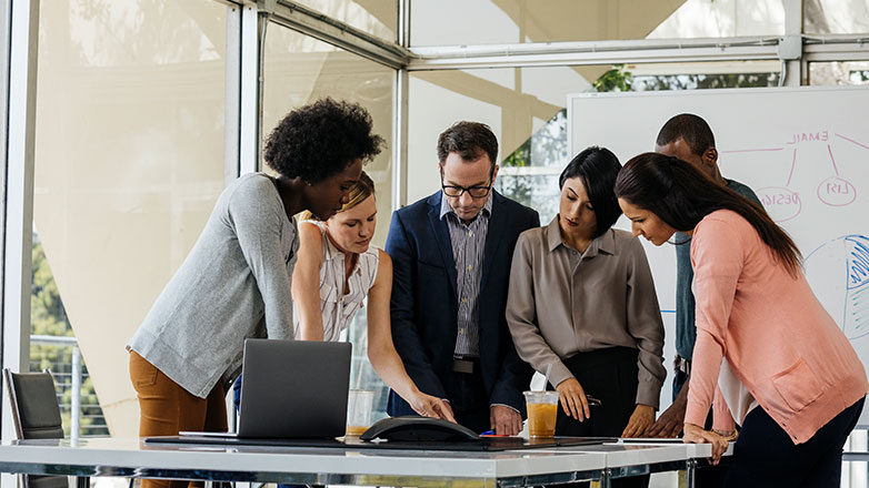 Group of coworkers looking at a table of papers.