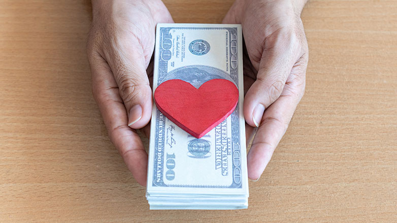 Hands holding money and heart decal.