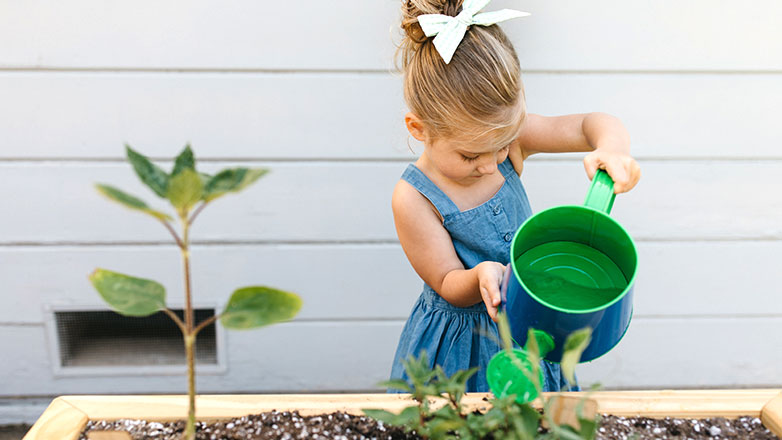 Young girl watering her garden plants.
