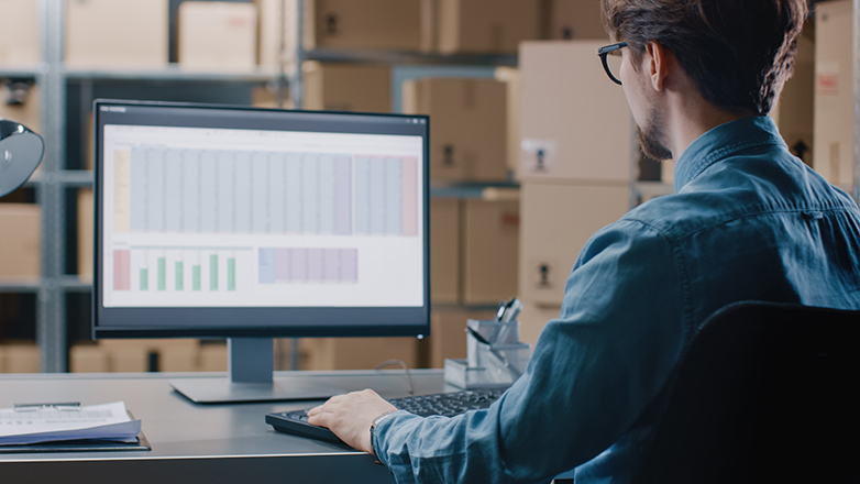 man at computer in warehouse from behind