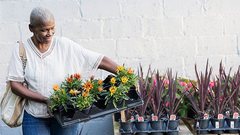 Mature woman picks up plants at a gardening store.