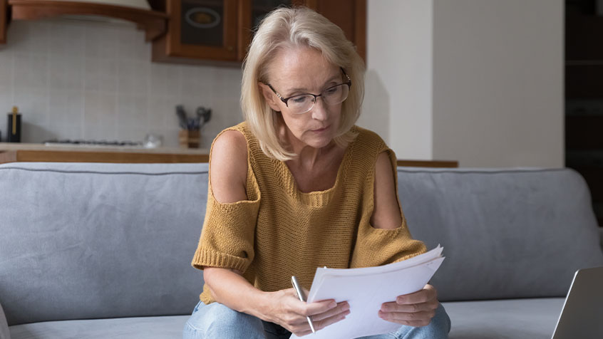 older woman reading paperwork with a serious face