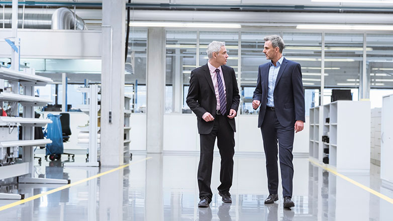Two men in a manufacturing facility having a discussion.