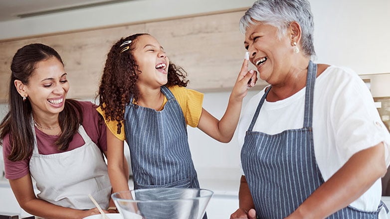 Grandma, mom, and granddaughter happily bake cookies together.