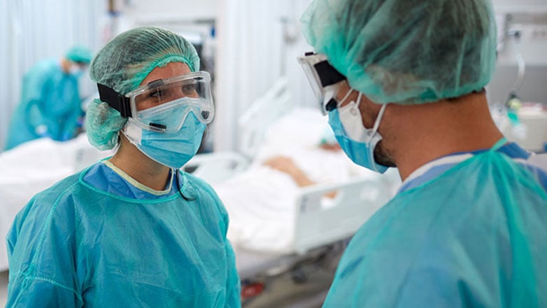 Two surgeons in the operating room discuss a patient's charts.