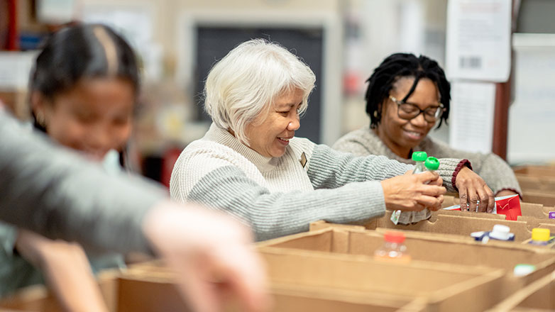 Volunteers pack food donation boxes together.