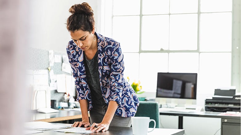 Female at her desk looking at paperwork.