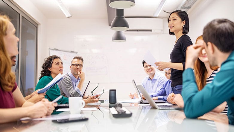 A woman speaks to her team at a meeting.