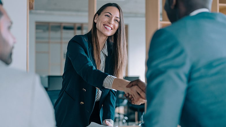 woman standing up to shake hand with another person.