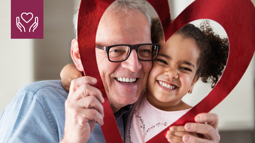 elderly man and little girl holding up heart frame