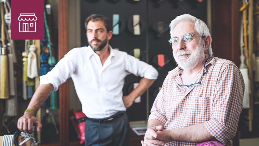 two business men, one old one young, gazing in a workshop.