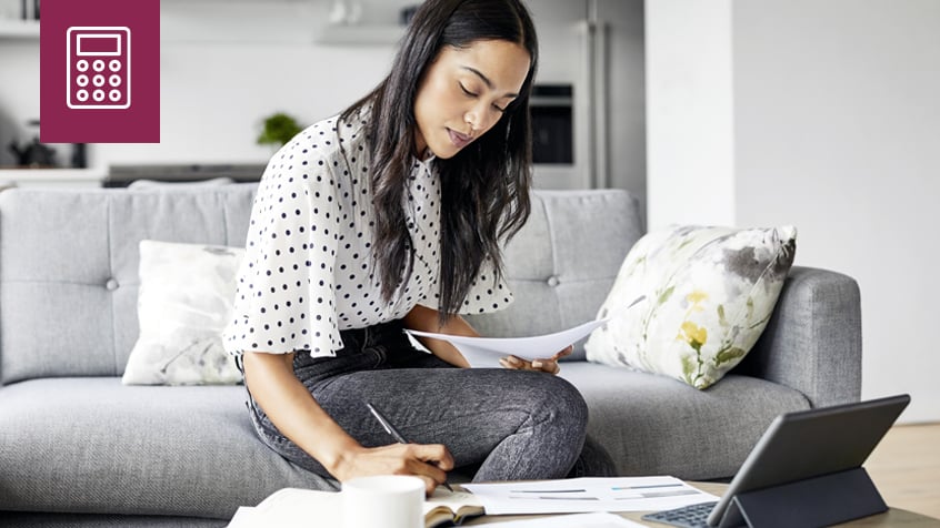 woman sitting on couch  with laptop and calculator