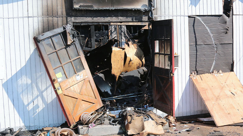 burned up store front with doors hanging open with smoke damage
