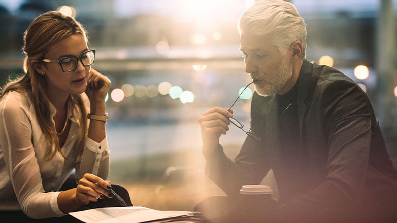 father and daughter review documents at table in business office