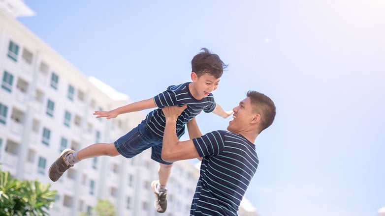 father raising son into the air outside