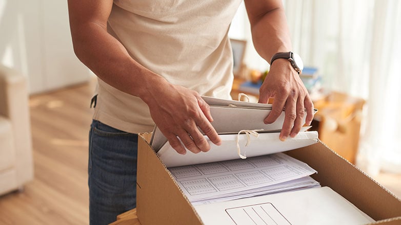 Man looking through a box of documents in a home office.