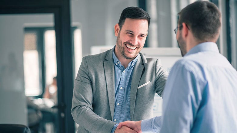 two business men shaking hands smiling