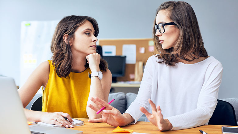 two woman reviewing at desk with laptop